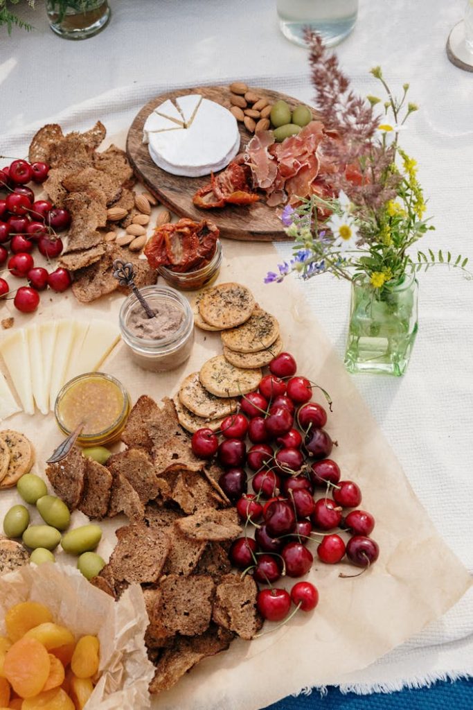 A delightful picnic spread featuring cherries, cheese, and a variety of snacks on an outdoor table.